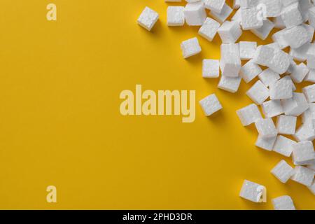 Many styrofoam cubes on yellow background, flat lay. Space for text Stock Photo