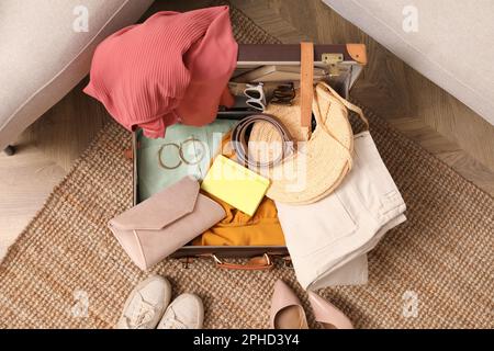 Open suitcase with different women clothes and accessories on carpet, top view Stock Photo