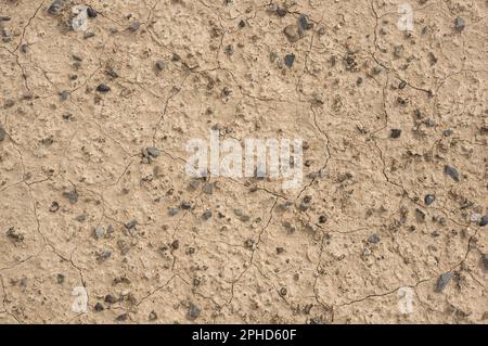 dry tan desert ground with cracked soil and pebbles Stock Photo