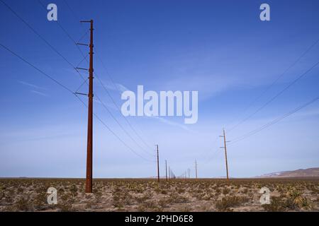 electric power lines in the desert with metal and wood poles Stock Photo