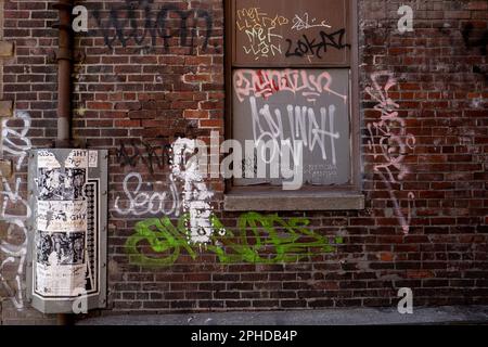 Downtown Seattle Alleyway with colorful Graffiti and paper prints on brick walls, windows and pipes Stock Photo
