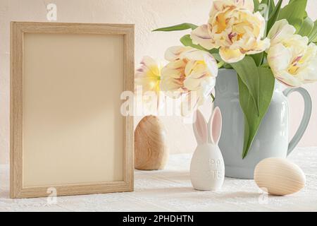 Wooden frame with copy space, tulips in vase and Easter decorations on table Stock Photo