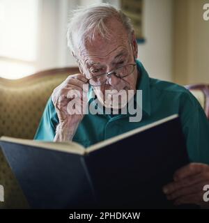 Reading takes me places Im incapable of going. a senior man reading a book while relaxing at home. Stock Photo