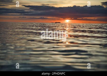 Picturesque sunset on the beach of Siquijor in the Philippines, the whole cloudy sky glows in fire red and golden orange color. Stock Photo