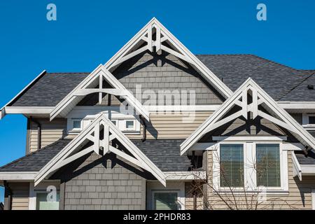 Roof shingles on top of the house against blue sky. Dark asphalt tiles on the roof background. black shingles, roof tile. Nobody, Selective focus, str Stock Photo