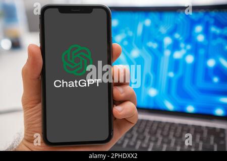 ChatGPT logo of neural network on the screen of smartphone in mans hand and laptop with neuronet on the splash screen on the background. Artificial intelligence concept. March 2023, Prague, Czech Republic  Stock Photo