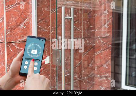 Cropped image of female entering secret key code for getting access and passing building using application on mobile phone, woman pressing buttons on Stock Photo