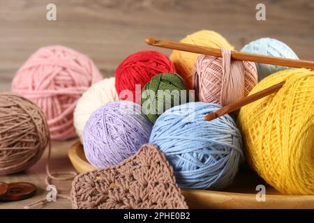 Many different clews of colorful knitting threads and crochet hooks on wooden table Stock Photo