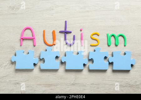 Flat lay composition with jigsaw puzzle pieces and word Autism on wooden background Stock Photo