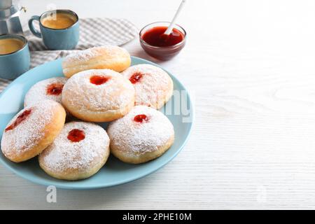 Delicious jam donuts served with coffee on white wooden table. Space for text Stock Photo