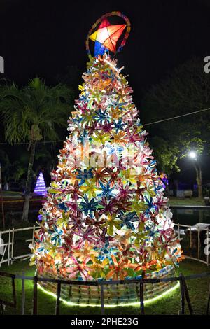 Colorfully lit fir tree with Christmas decorations in Siquijor in the Philippines made from recycled material. Stock Photo