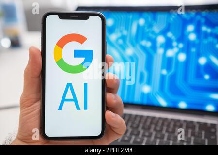Google AI logo of neural network on the screen of smartphone in mans hand and laptop with neuronet on the splash screen on the background. Artificial intelligence concept.  Stock Photo