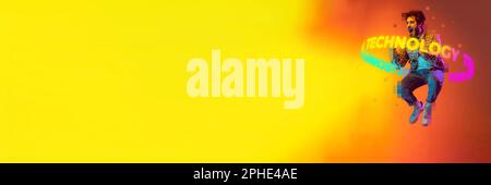 Banner with jumping and screaming man with neon lettering technology around body over yellow and orange background. Copy space for ad Stock Photo