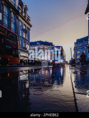 A red double decker bus travels in the rain down Oxford Street in London. Stock Photo