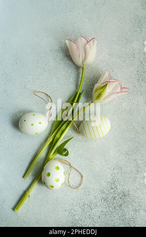 Flat lay with colored eggs and tulips on concrete background Stock Photo