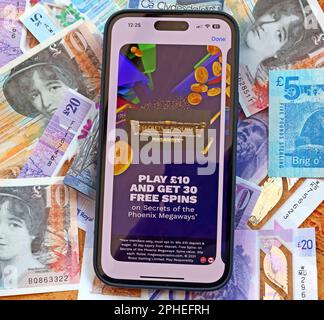Tempting Free Spins - Online and smartphone casino, slots and gambling app with Scottish Sterling notes, money easily lost - BeGambleAware Stock Photo