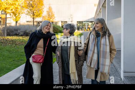 Three senior women walking through the city streets, retired females in a moment of relaxation outdoors Stock Photo