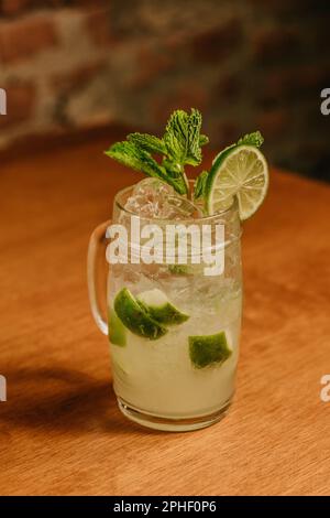 A vibrant mason jar filled with a refreshing cocktail and garnished with slices of lime and mint leaves Stock Photo