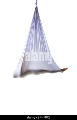 Athletic young man lying in silk hammock, training, doing aerial gymnastics and yoga exercises against white studio background Stock Photo