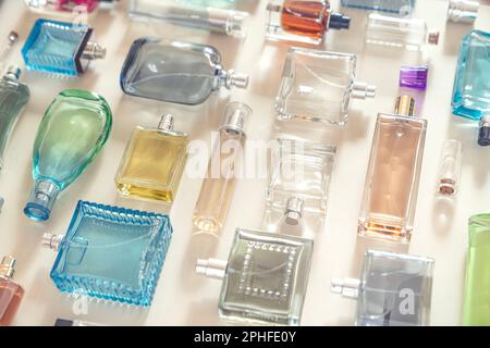 Perfumery, cosmetics and beauty industry background. A lot of transparent bottles of perfume and cologne and toilet water lie neatly on a beige backgr Stock Photo