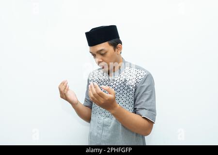 Asian Indonesian Muslim man raises his hands for praying gesture Stock Photo