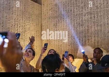 People / Tourists taking photos of the hieroglyphics in an underground burial chamber inside the Pyramid of Unas at Saqqara Necropolis in Giza, Egypt Stock Photo