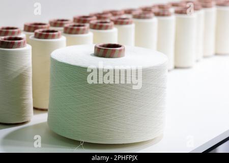 White cotton thread spools used in fabric and textile industry. Selective focus. Stock Photo