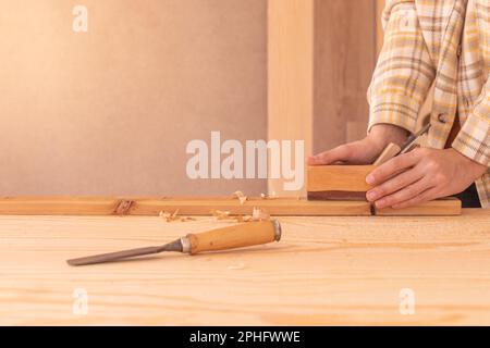 Workman using jack plane on wooden board. Crop faceless male carpenter smoothing wooden detail with jack plane Stock Photo