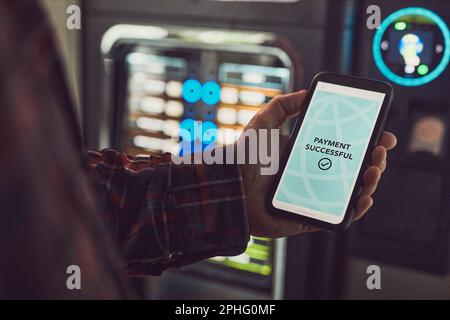 Consumer paying for product at vending machine using contactless method of payment with mobile phone. Man using payment app on smartphone to buy produ Stock Photo