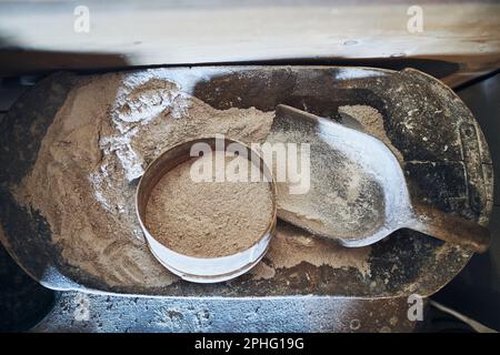 Sifting flour. Bolting flour. Flour in wooden bowl. Old rustic kitchen utensils Stock Photo