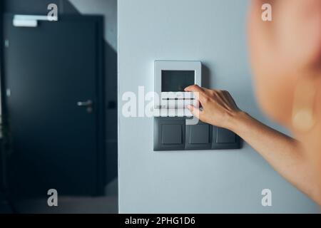 Woman controlling office with digital touch screen panel installed on the wall in office. Concept of smart remote control. Managing system at work. Wo Stock Photo