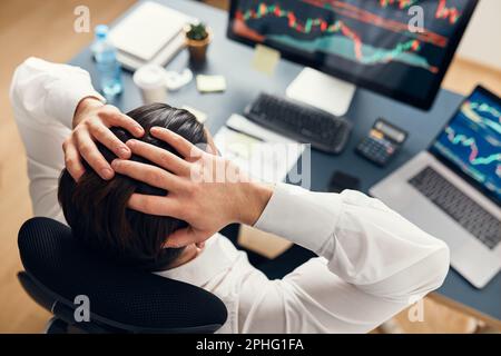 Worried businessman looking at charts stressed by news from stock market. Investor lost money online. Man analyses loss and profit. Businessman invest Stock Photo