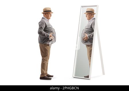 Full length profile shot of a senior man with a big belly standing in front of a mirror isolated on white background Stock Photo