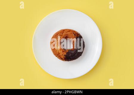 old fashioned doughnut chocolate on plate isolated on yellow background Stock Photo
