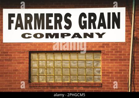 2019 02 08 Wakita Oklahoma USA - Farmers Grain Company sign above glass block window in brick building with messy wires Stock Photo