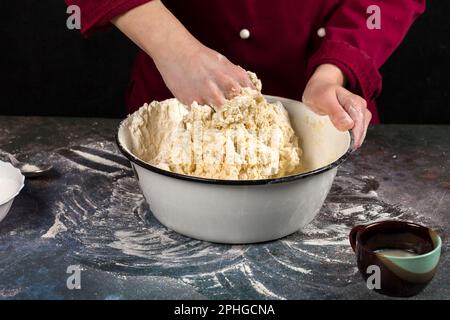 The chef mixes the flour with yolk with his hand. Professional cook makes yeast dough Stock Photo