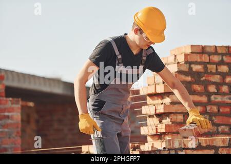 Installing brick wall. Construction worker in uniform and safety equipment have job on building Stock Photo