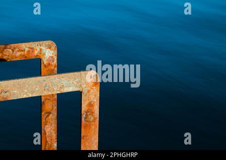 Rusty Metal Ladder On A Quay Contrasted Against The Blue Sea, Mudeford Quay, Christchurch England UK Stock Photo