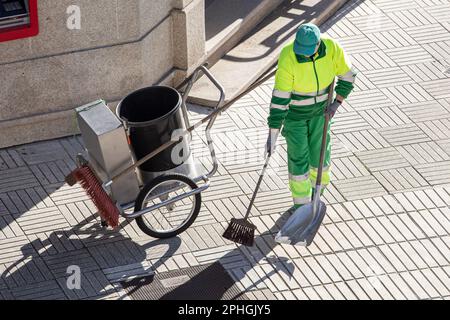 Street sweeper working on a sidewalk with her shovel, cart and broom. Urban cleaning concept Stock Photo