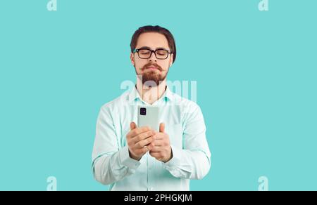 Serious man with mobile phone watching media content, reading messages or types of feedback. Stock Photo