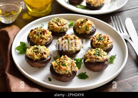 Stuffed mushrooms with cream cheese, bread crumbs and nuts on plate over wooden background. Close up view Stock Photo