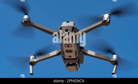 A flying mini drone recording video and photos in the blue sky Stock Photo