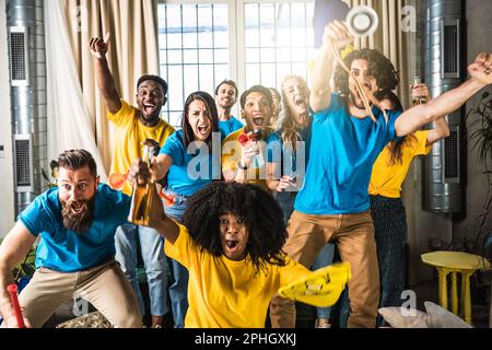 Multiethnic joyful sport fans watching game on TV at home - Supporters having fun on sofa for competition event on TV - Friends celebrating victory wh Stock Photo