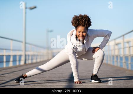 Sporty Young Black Female In Activewear Warming Up Before Jogging Outdoors Stock Photo