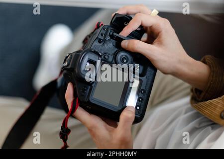 Rear view of male photographer holding camera working with photos, looking through taken pictures, blank screen mockup Stock Photo