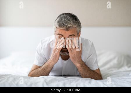 Exhausted middle aged man lying in bed in the morning Stock Photo