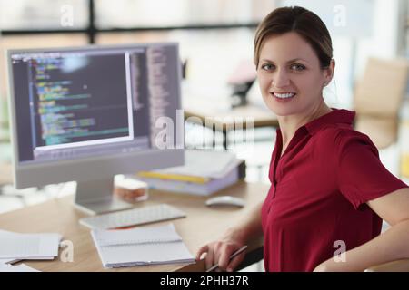 Smiling woman app developer writes code in company office Stock Photo