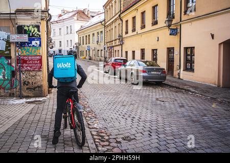 Wolt Courier on bicycle. Wolt is a Food Delivery service. Vilnius, Lithuania - March 10, 2023. Stock Photo