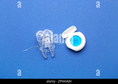 Case with dental floss and model of tooth on blue background Stock ...