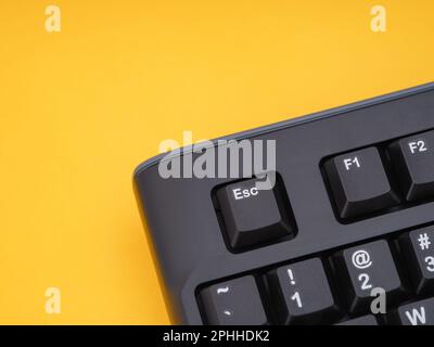 A black computer keyboard on a yellow background. Close up. Stock Photo